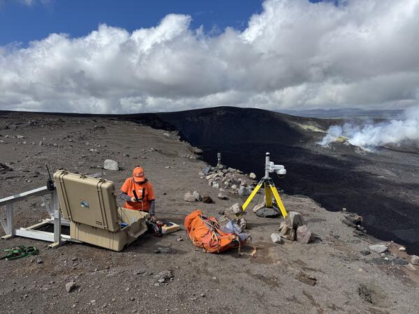 Color photograph of scientists deploying webcamera on volcano