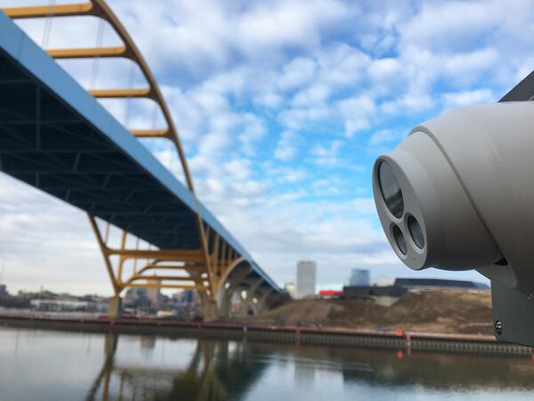 Close up view of webcam pointed towards urban river and bridge in background