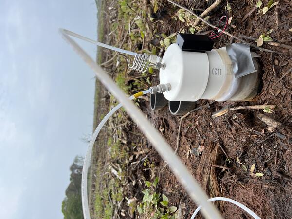 a sensor sits halfway out of the ground with two tubes sticking out of it surrounded by grass