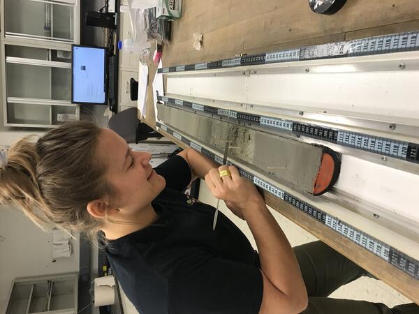 USGS scientist Jessica Rodysill studies a sediment core to identify storm deposits and help understand past hurricane activity. This core was collected from the Dominican Republic.