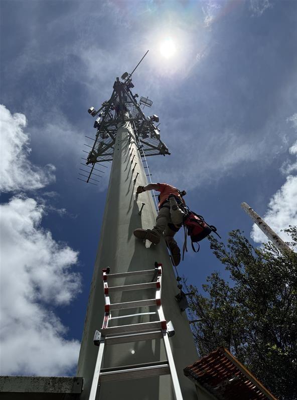 Color photograph of field engineer climbing tower