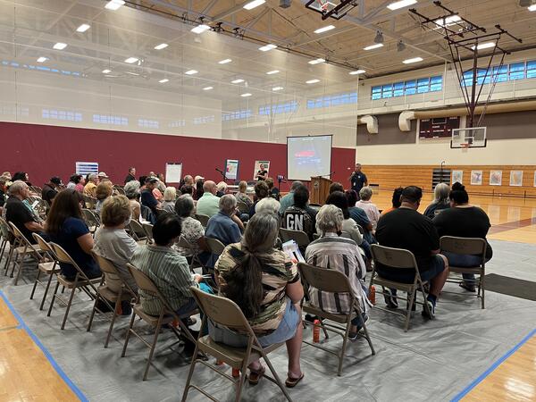 Color photograph of person presenting to an audience in a gymnasium