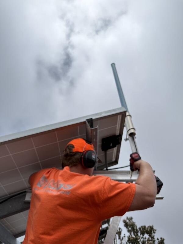 Color photograph of field engineer working on antenna at volcano monitoring site
