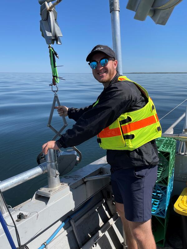 Scientist on boat holding microplastics sampler