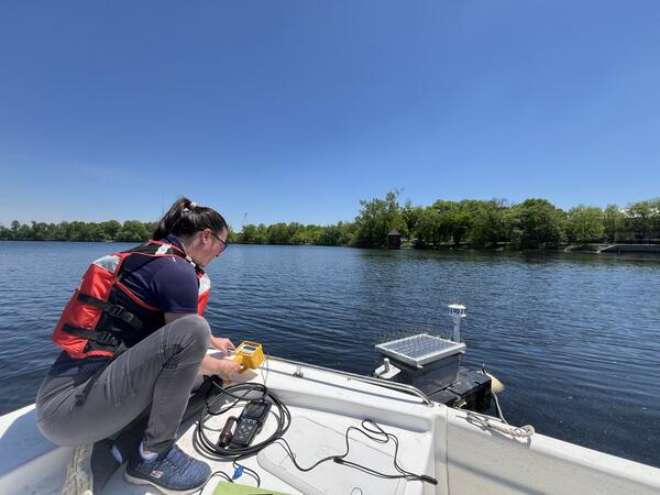 Scientist using equipment on boat in pond