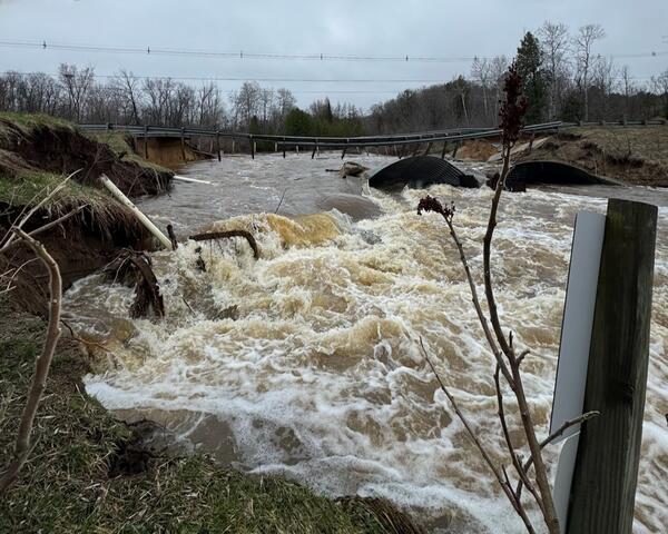 Washed out bridge over raging flood waters on a gray day