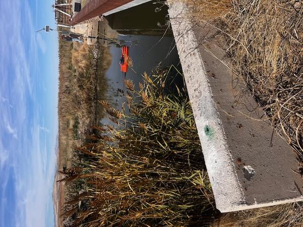 View across river next to low bridge with gage on opposite side.