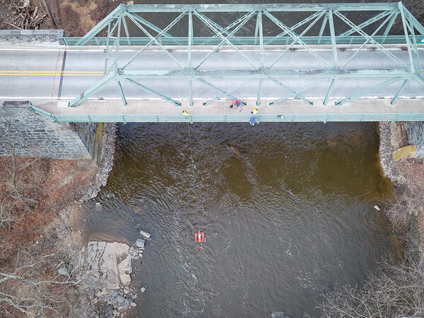 An aerial view of hydrologic technicians on a truss bridge above Brandywine Creek measuring streamflow with an ADCP.