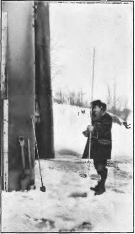 Black and white historic picture of a scientist holding a measuring rod in a hole chiseled in the ice below him