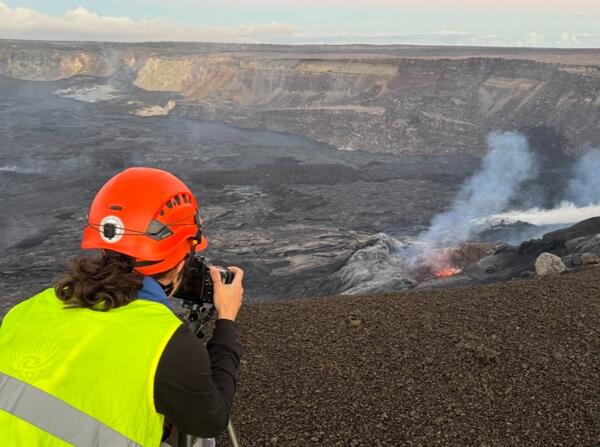 Color photo of a USGS scientist taking photos of the lava spatter inside the north vent.