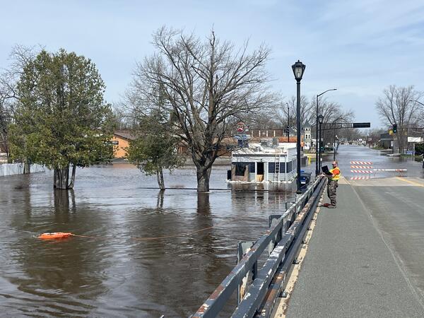 Hydrologic technician takes acoustic Doppler current profiler measurement of flooded river from bridge