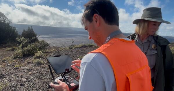 Color photo of USGS scientist and National Parks Service staff looking at the UAS operation screen. 