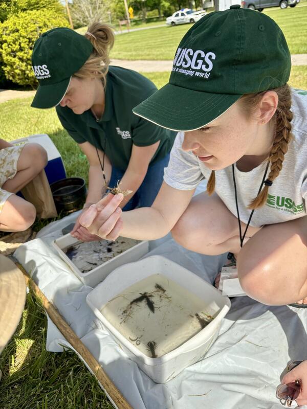 Two women with USGS hats hold a crayfish