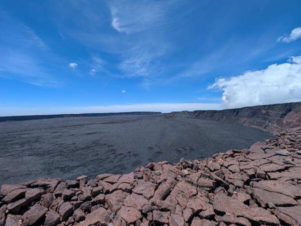 Color photograph of caldera with blue sky in the background