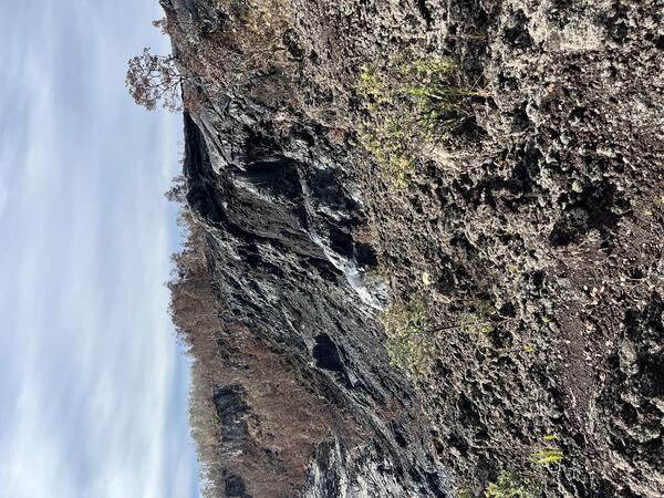 Color photograph of cooled lava draped over crater wall