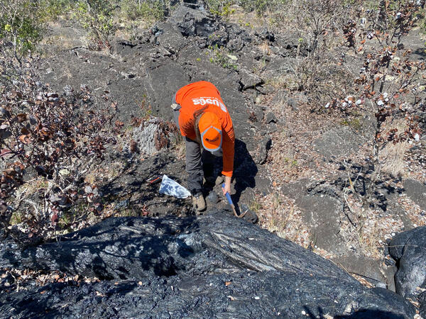 Color photograph of scientist taking a cold lava sample