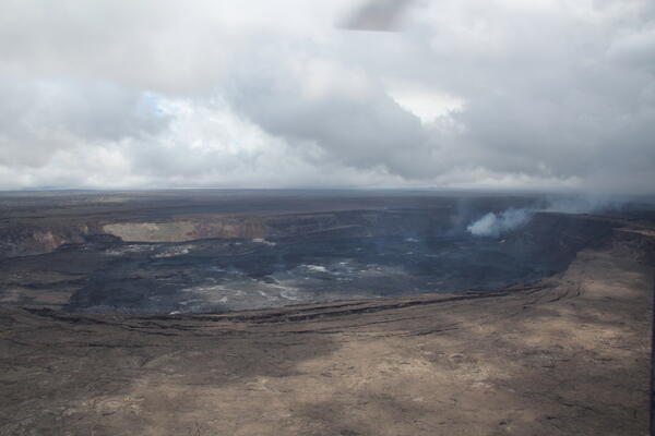 Color photograph of a caldera with an actively degassing vent near one wall