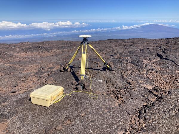 Color photograph of tripod on lava flow with mountain in the background