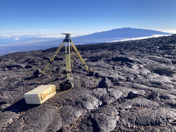 Color photograph of tripod on lava flow with mountain in the background