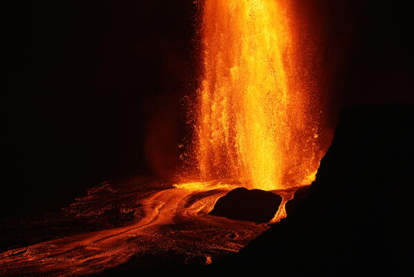 Color photograph of a lava fountain erupting at night