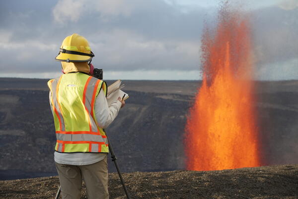 Color photograph of scientist observing lava fountain