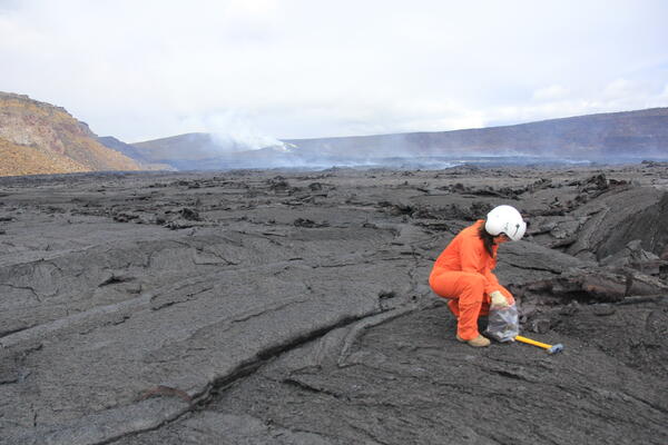 Color photograph of scientist collecting lava sample