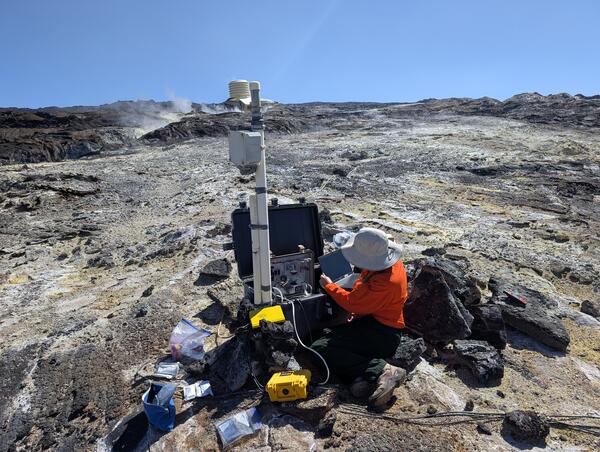 Color photograph of scientist working on volcanic gas monitoring instrumentation