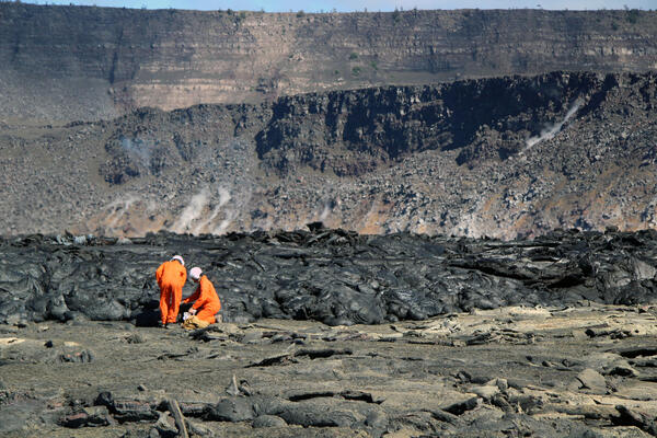 Color photograph of scientists collecting sample on crater floor