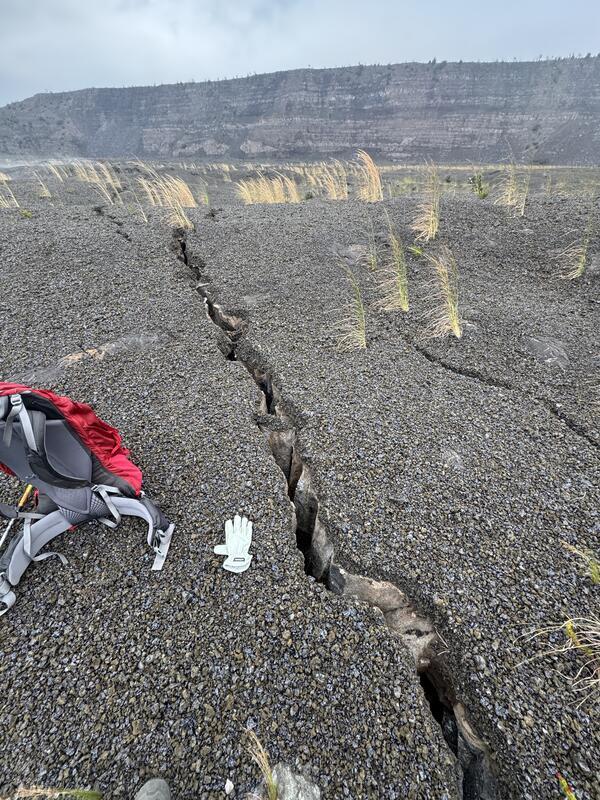Color photograph of backpack next to cracks on ground