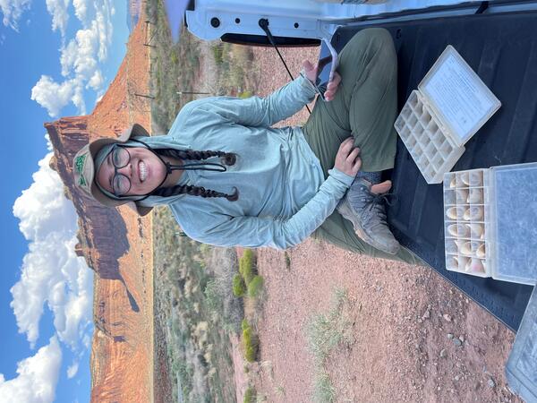 A person smiles while collecting soil stability data in southern Utah