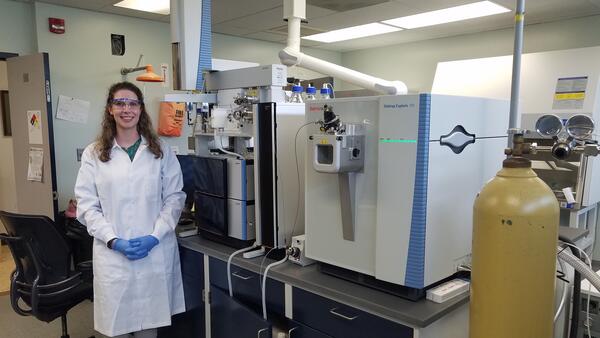 Scientist standing in a laboratory next to an instrument