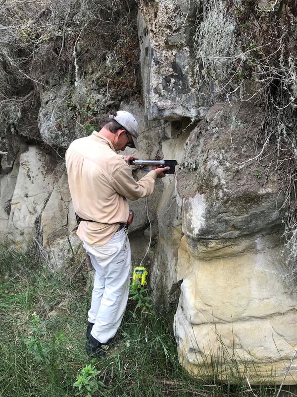 Geologist using instrument to test rock permeability