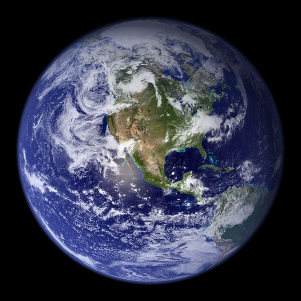 A vibrant blue image of Earth with swirling white clouds and brown landmasses 
