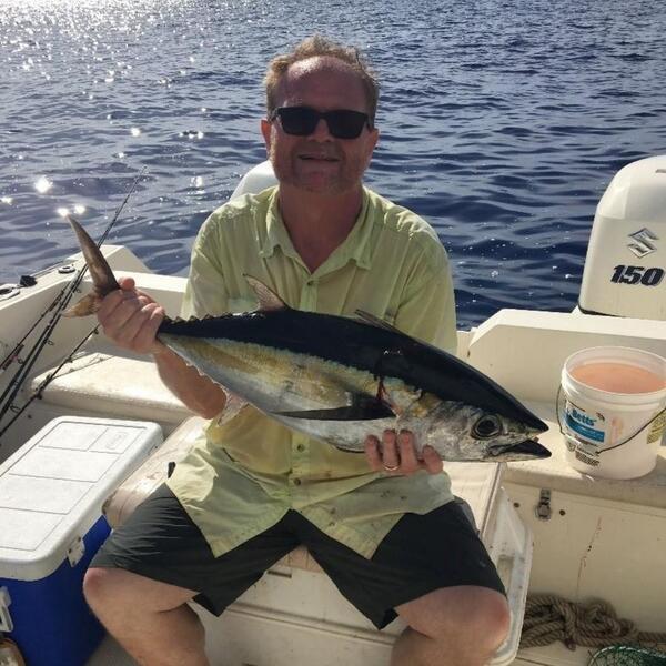 Scientist Doug Beard holding a fish with both hands on a boat on the water.