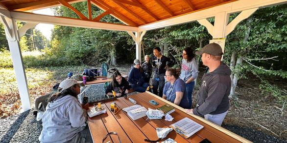 a group of volunteers and scientists watches a bander place a band on bird 