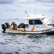 Two researchers on the R/V Dragonfly deploy a long yellow Autonomous Underwater Vehicle in Lake Michigan.