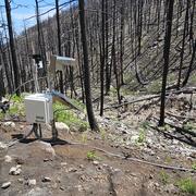 Equipment on a hillslope that is covered with rocks and burned trees