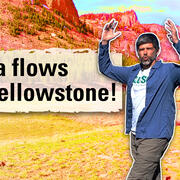 Thumbnail image of a man with his arms in the air in a meadow with cliffs in the background