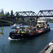 boat with onboard crane goes through the blue canal waterway on a clear sky day