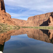 The Colorado River water reflects blue skies and red Grand Canyon walls