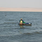 Person pushes a raft with equipment out to equipment in thigh deep choppy water