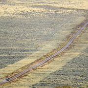 aerial view of a road, with mowed areas of sagebrush right next to the road and a Jeep driving