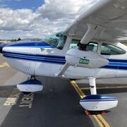 a small white aircraft with a blue, white, and black stripes running down the middle and plane nose.