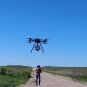 A person operates a drone in a grassland prairie