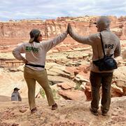 A USGS and NPS scientist give each other a high-five while doing fieldwork