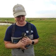 Woman wearing cap and waders, holding a duck