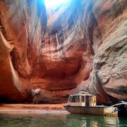 USGS boat parked in serene spot on Lake Powell where light streams through hole at cliff tops