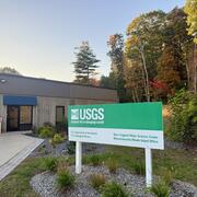 USGS Massachusetts office with a sign out front and trees in the back.