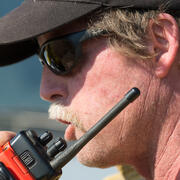 A closeup of a man talking into a handheld radio