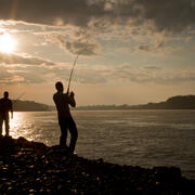 Two people fishing at sunset.